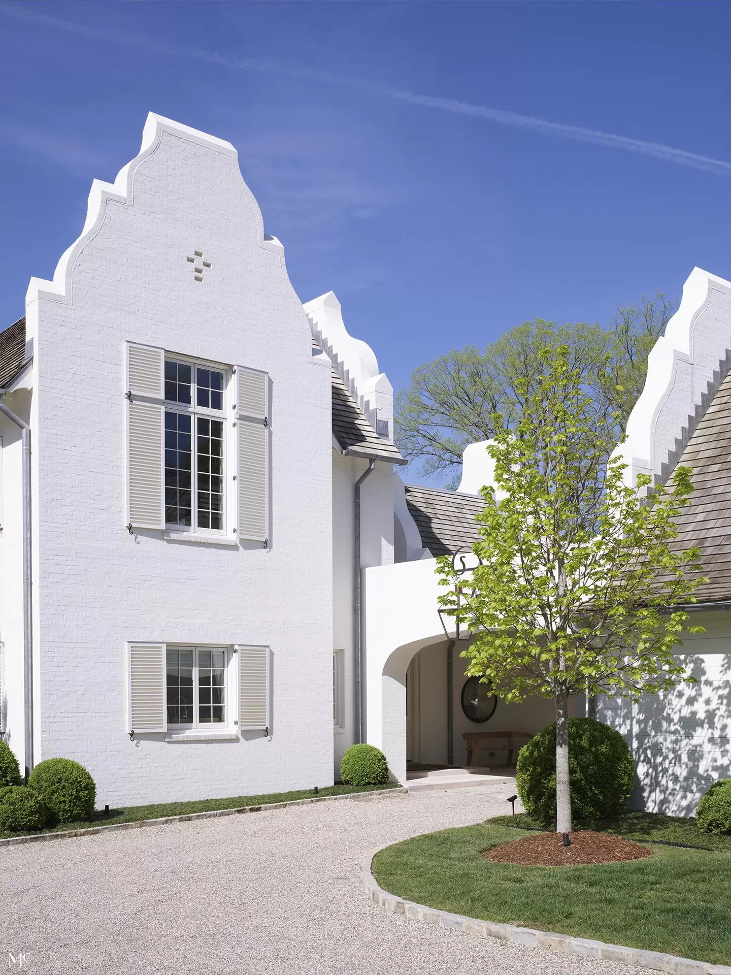 White brick and shingle ornate house with a tall gable roof, fluted window details, stone accents