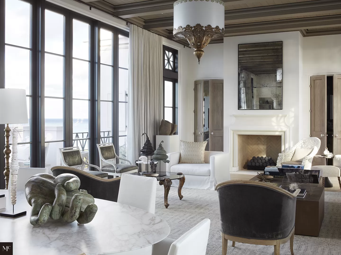 Floor to ceiling windows looking out to the ocean, with black and white simple furniture designs.