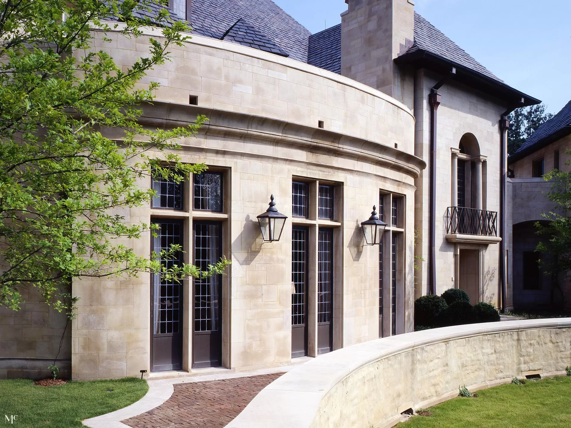 stone and stucco home with a circular wall, front door, French windows, large fluted window sills, bronze light fixtures