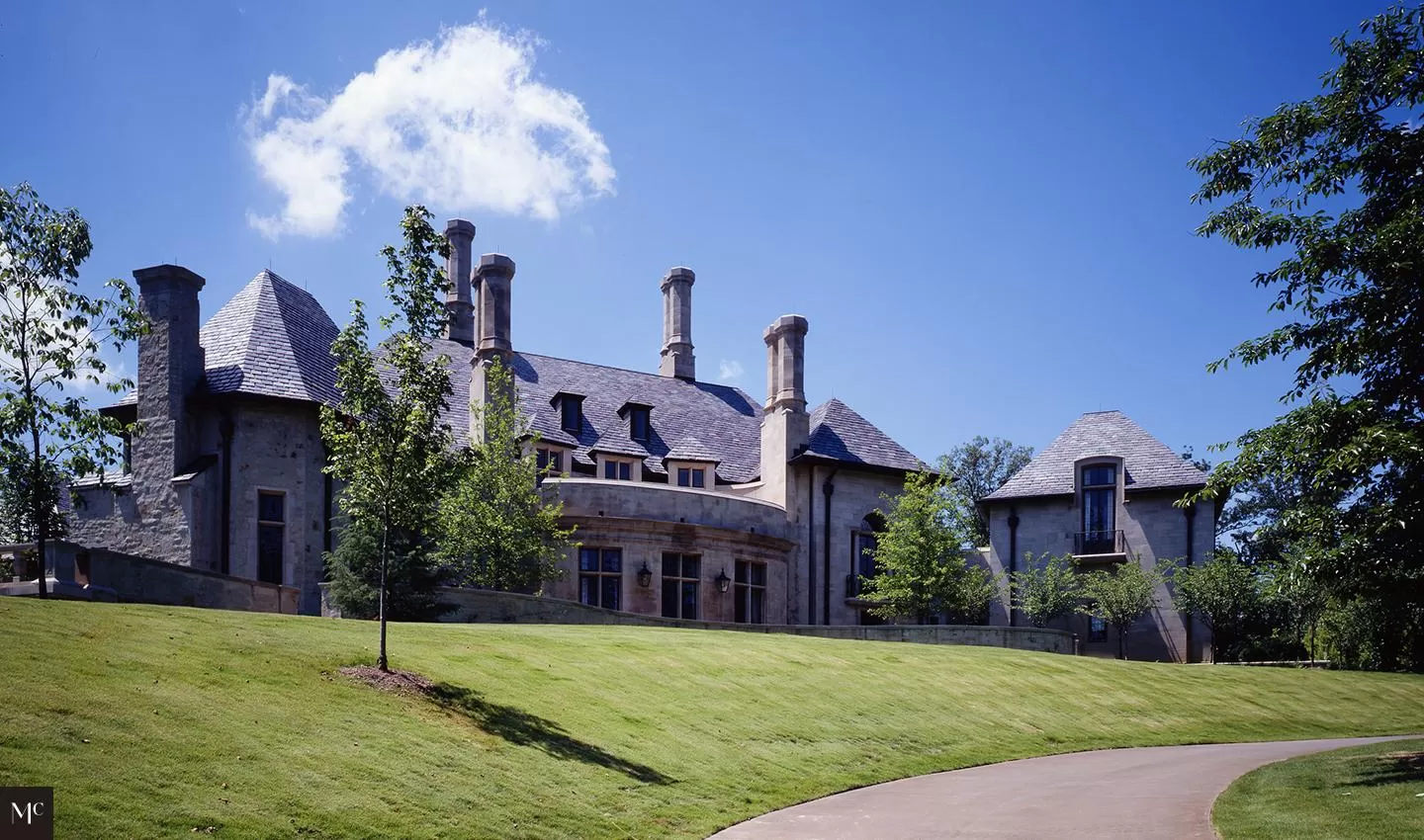 stone and stucco home with a circular wall, front door, French windows, large fluted window sills, bronze light fixtures