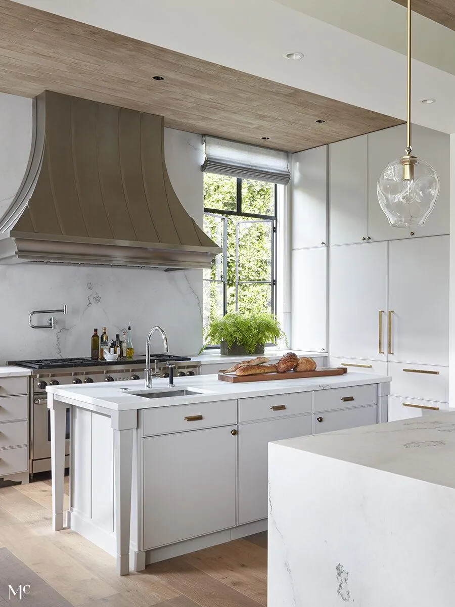 Kitchen with large glass doors leading to an outdoor dining area, featuring modern neutral-toned furniture, and natural light