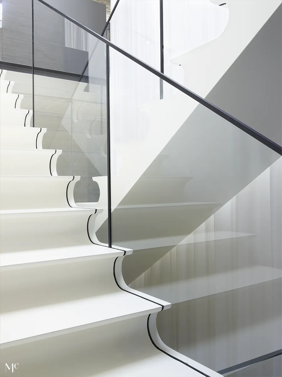 A minimalist staircase with white walls, wood slats, and black metal details