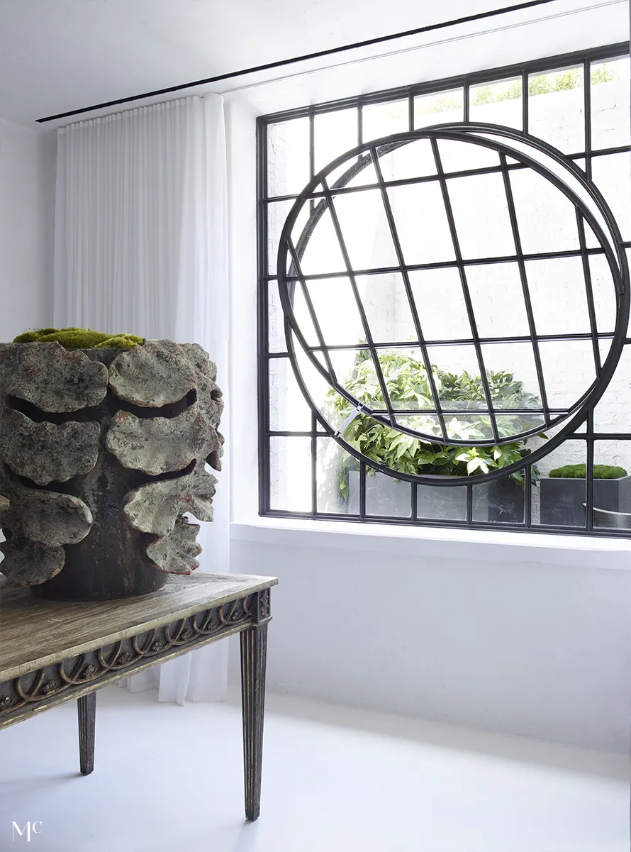 A contemporary interior featuring large windows, wooden furniture, black border accents, and minimalist white furniture