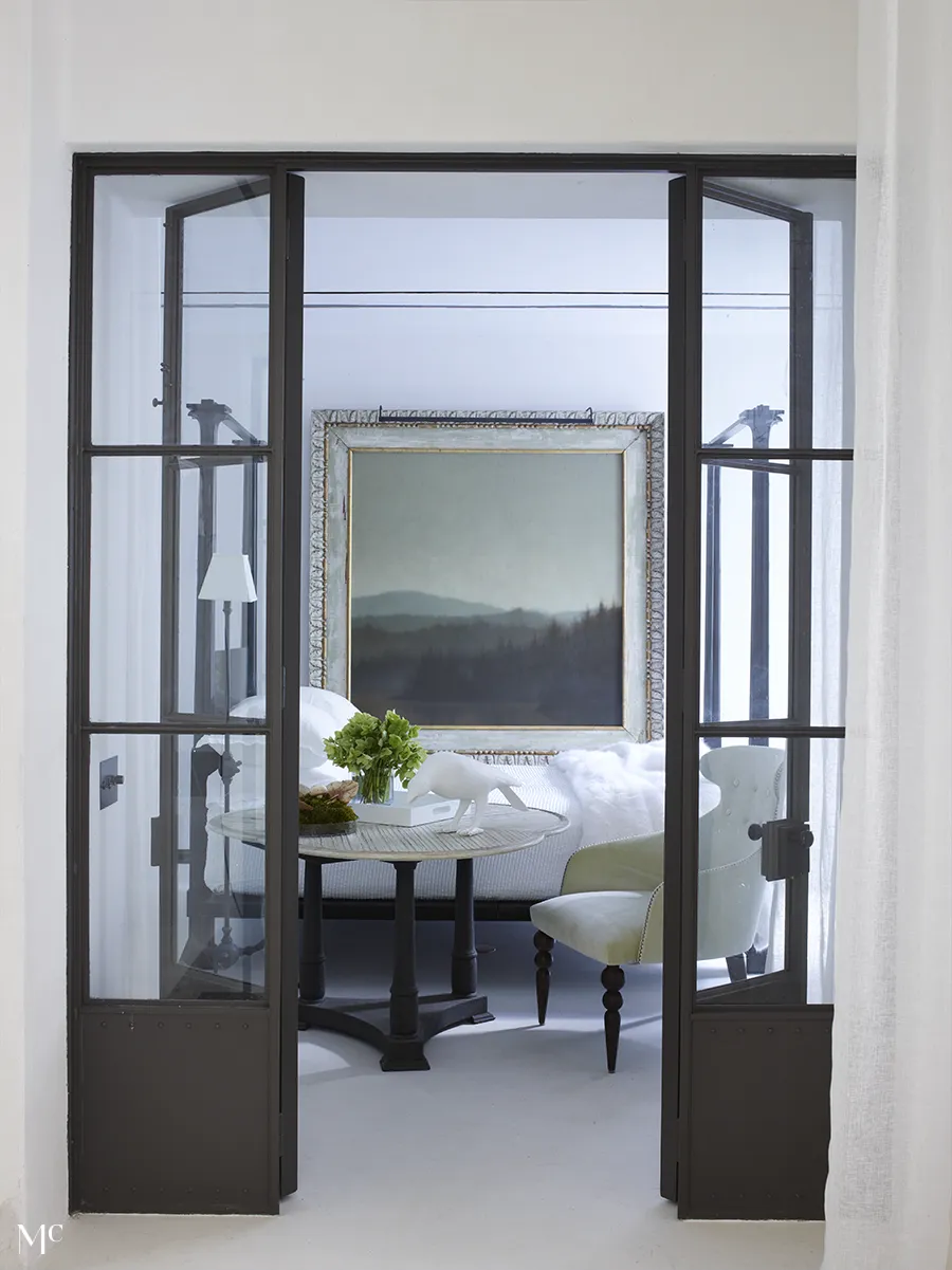 A contemporary interior featuring floor-to-ceiling doors, minimalist white furniture and black borders