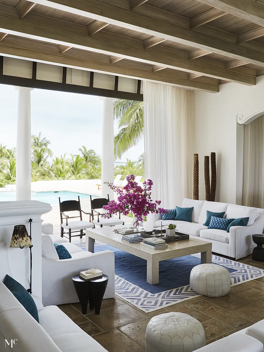 White furniture in a living room overlooking the pool and greeneries