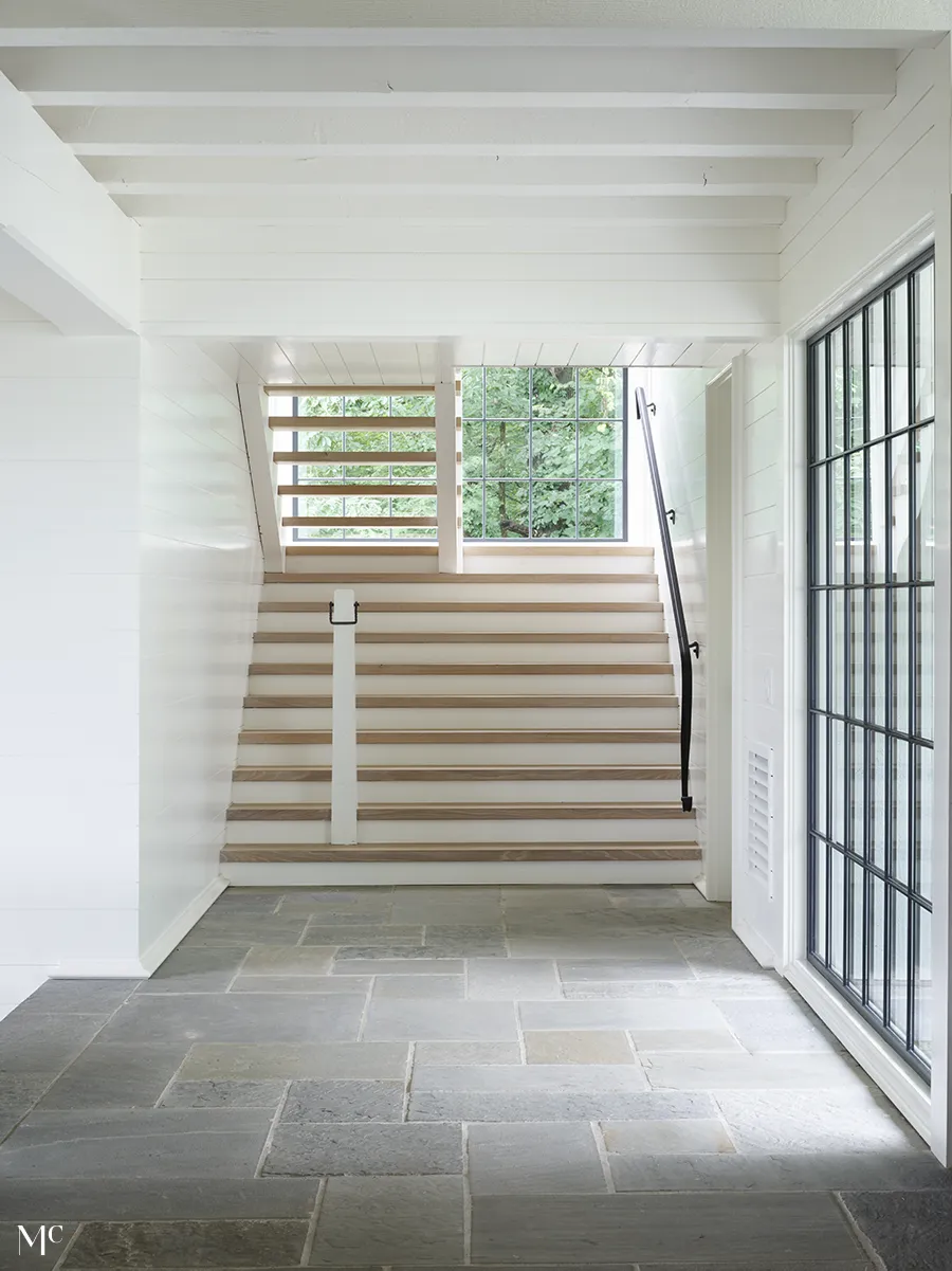 White interior with wooden stairs and black railway and window borders