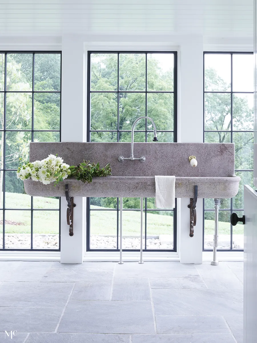 white marble interiors with stone sink and large floor to ceiling windows outlooking trees and lawns