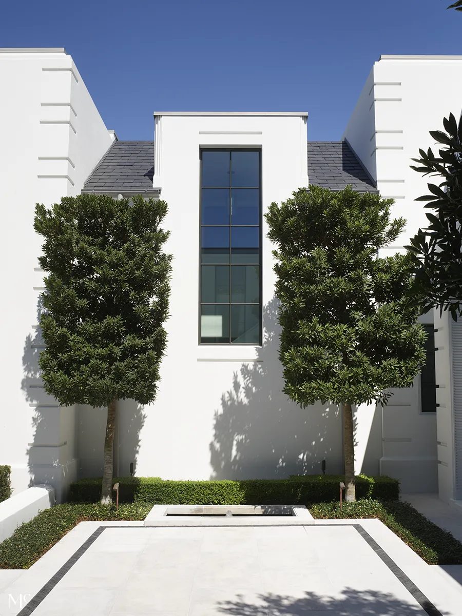 A symmetrical view of a large window with hedges on both sides