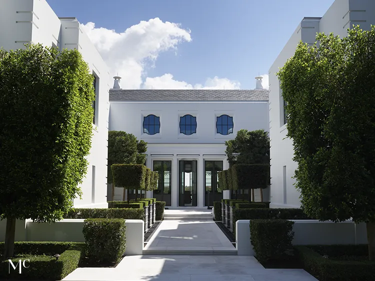 A symmetrical view of the front entrance to an all-white modern mansion with large black windows