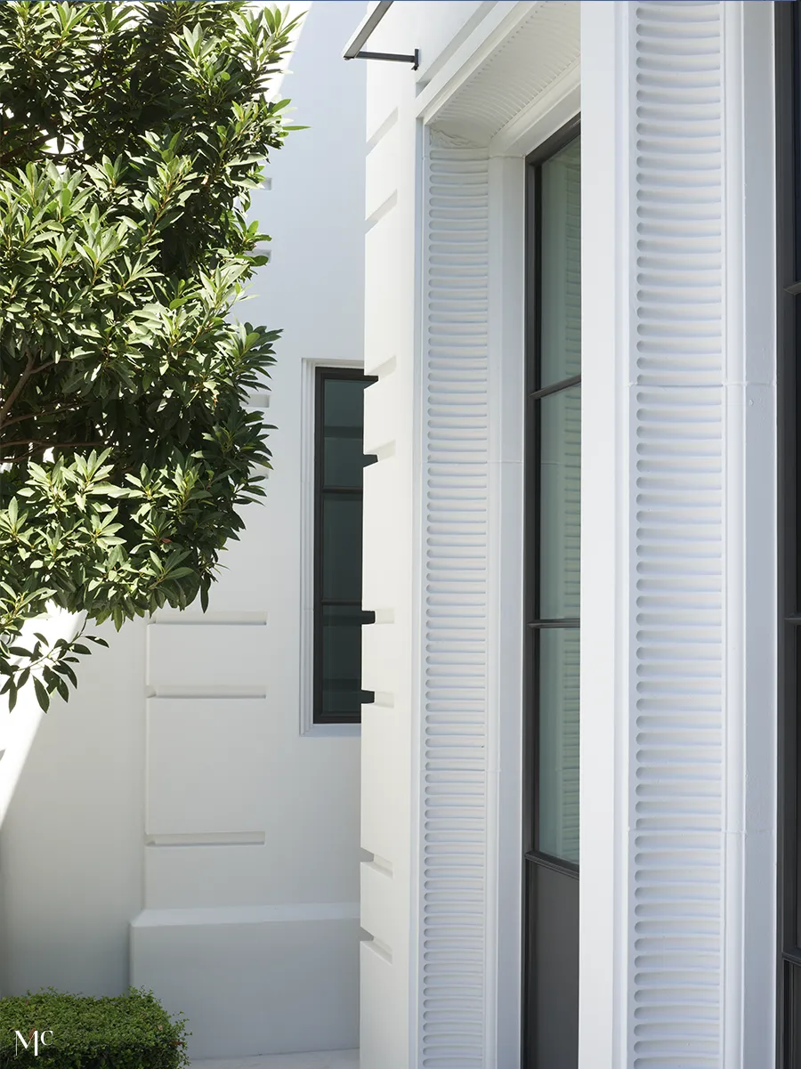 white exterior with windows with a tree on the side