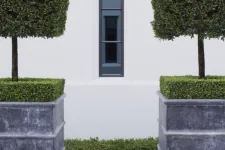 A symmetrical view of a window with hedges on both sides