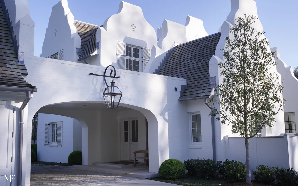 White brick and shingle ornate house with a tall gable roof, fluted window details, stone accents