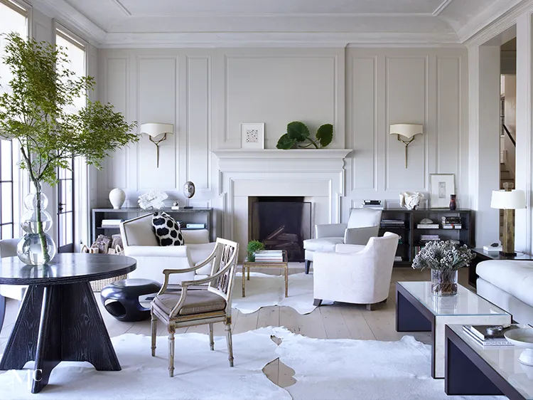 A large living room with white walls, black and silver accents, a dining table in the center of an all-white space