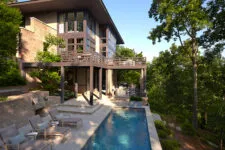 A modern, two-story home with a large outdoor patio and pool, in the style of modernist architecture, overlooking lush green trees