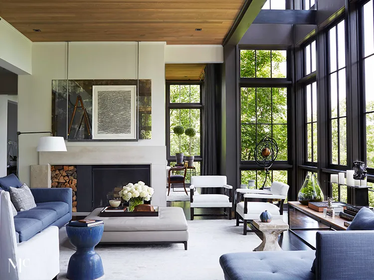 A modern farmhouse-style living room with a fireplace, blue accents, and large windows