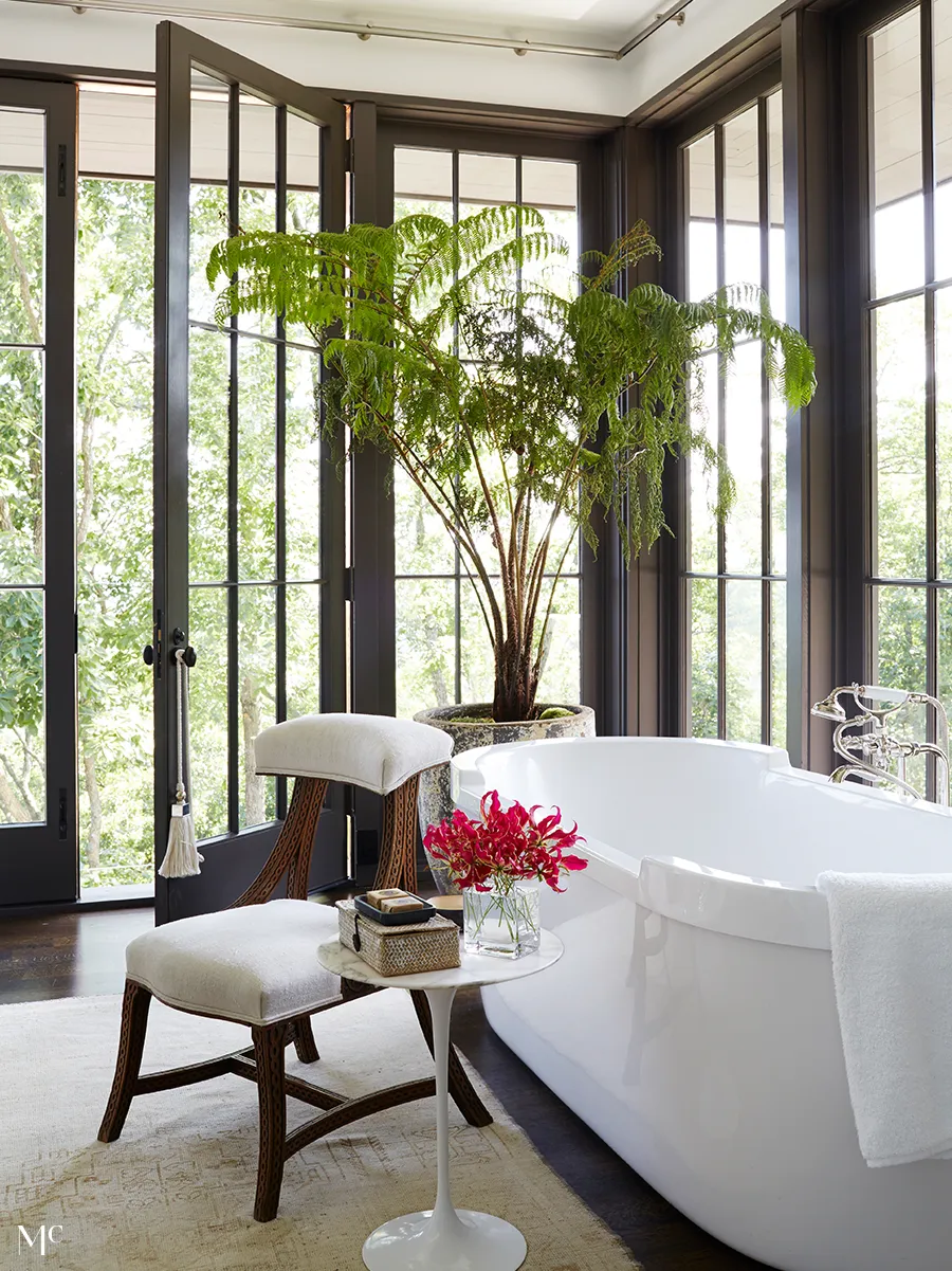 A modern bathroom with large windows overlooking lush green trees