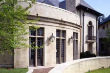 stone and stucco home with a circular wall, front door, French windows, large fluted window sills, bronze light fixtures