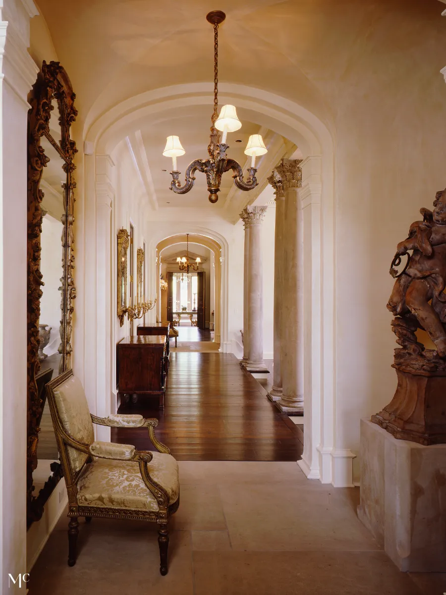 Elegant hallway with tall arched ceilings and white walls, dark wood floors