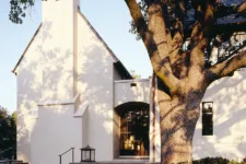 simple and elegant house, featuring large windows, white walls, a gable roof, and stone accents