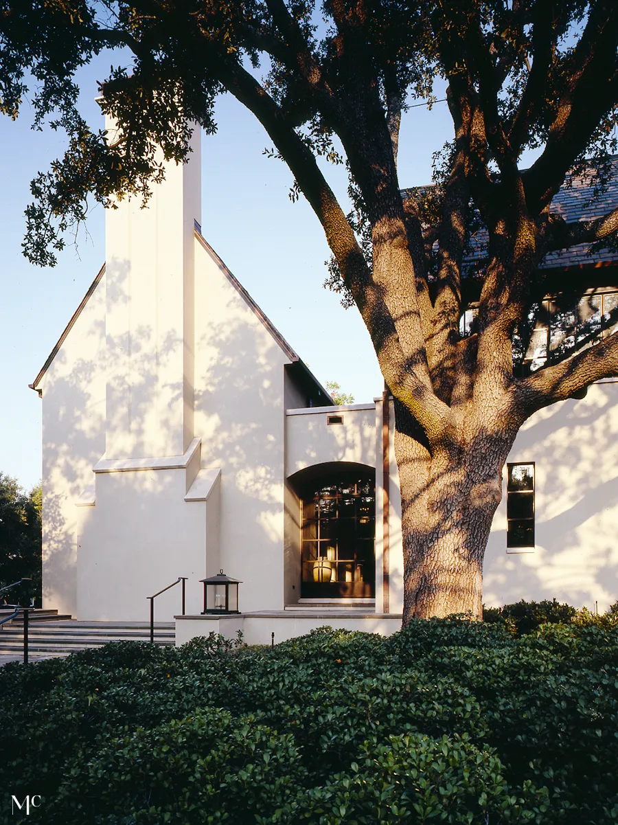 simple and elegant house, featuring large windows, white walls, a gable roof, and stone accents