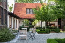 classic colonial-style white house with black shutters, front view, blue door, and large trees in the yard, with navy-blue details, white walls