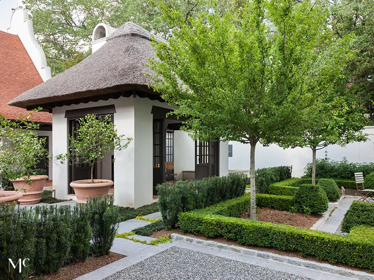 classic colonial-style white house with black shutters, front view, blue door, and large trees in the yard, with navy-blue details, white walls