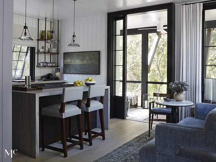 Photo of a kitchen island with barstools, entry door open to the outside